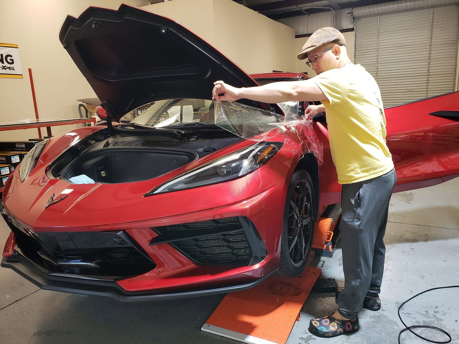 Paint protection film being laid over the front of a red C8 Corvette