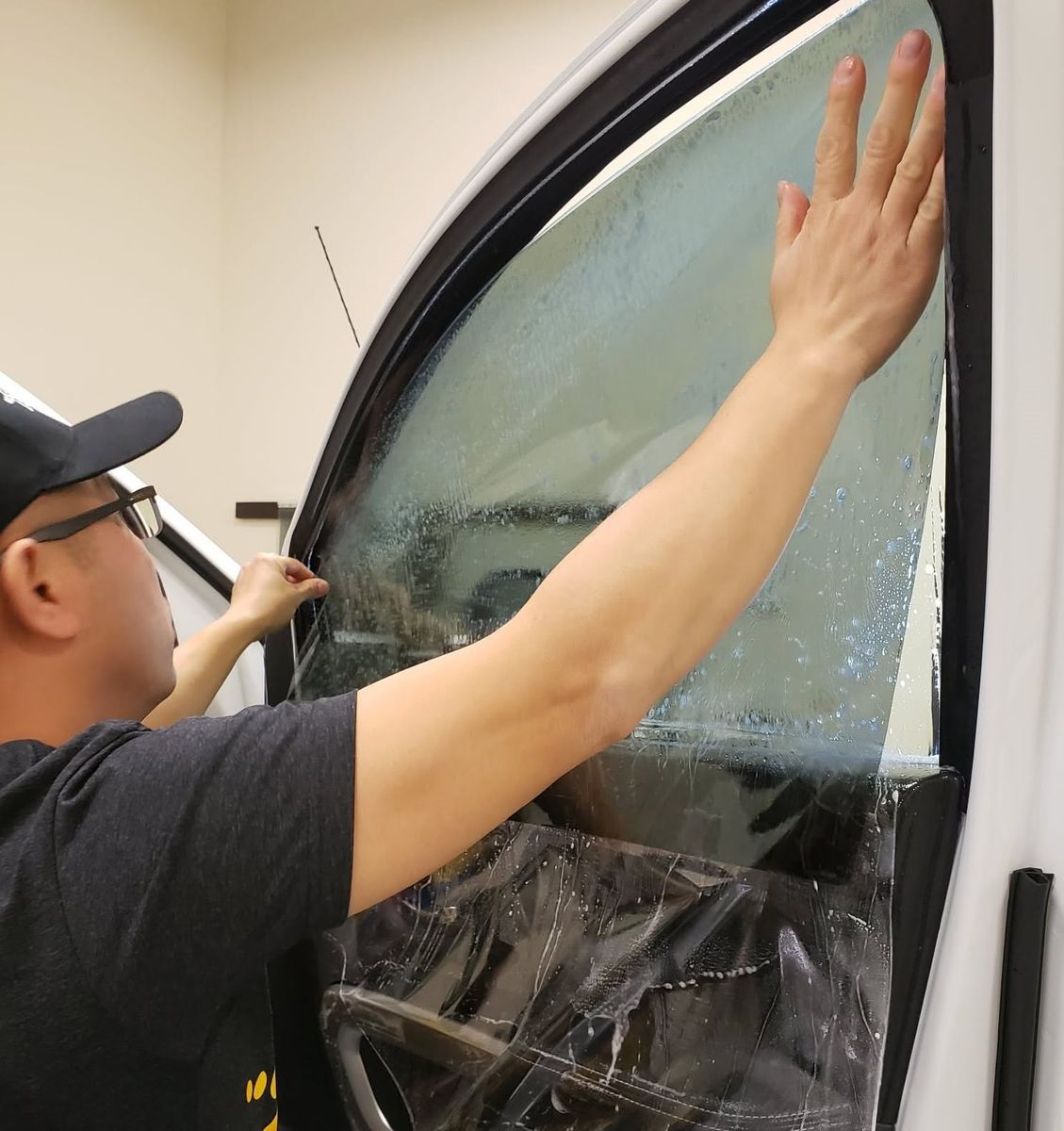 Vang Ge Lee setting window film on the door glass of a truck