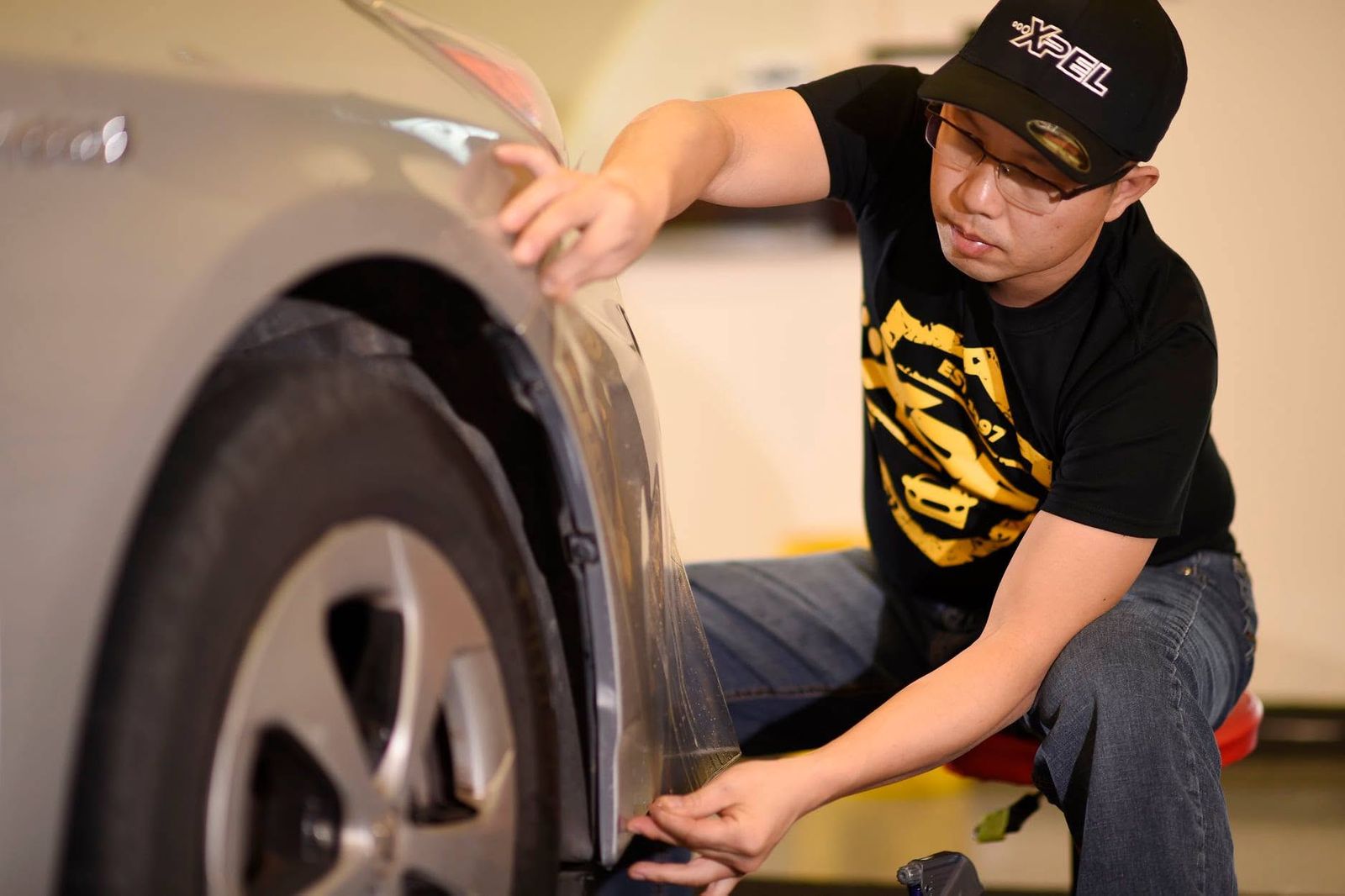 Vang Ge Lee, owner of Auto Armor Owasso, fitting paint protection film over a front fender